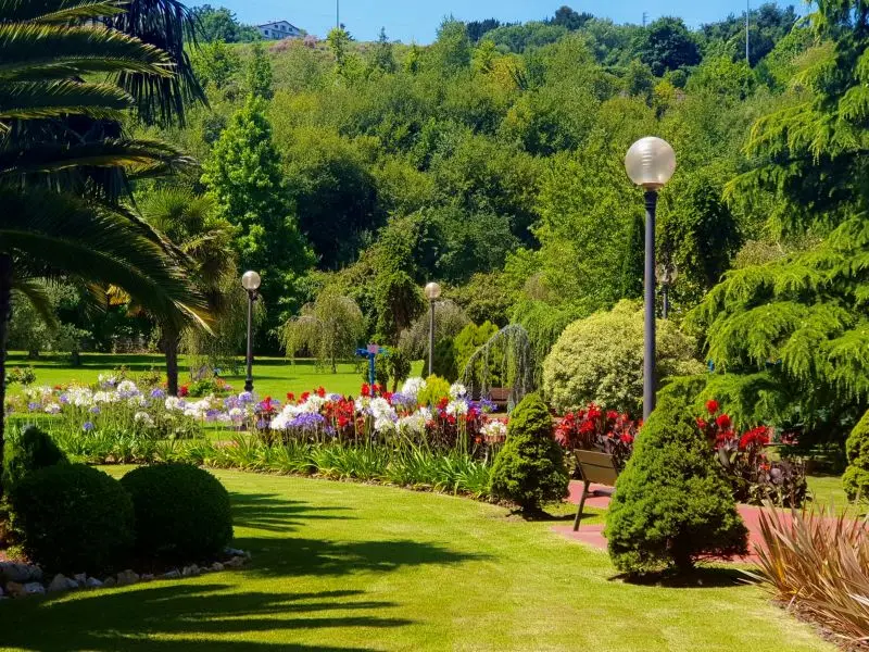 Jardín amplio con parterres de flores, césped y arbolado
